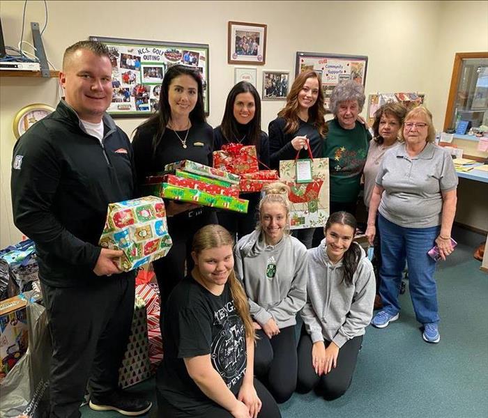 Group of SERVPRO employees and volunteers holding Christmas gift donations for Toys for Tots